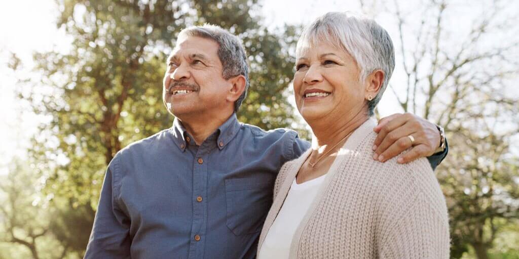 A senior couple is standing outdoors admiring the view.