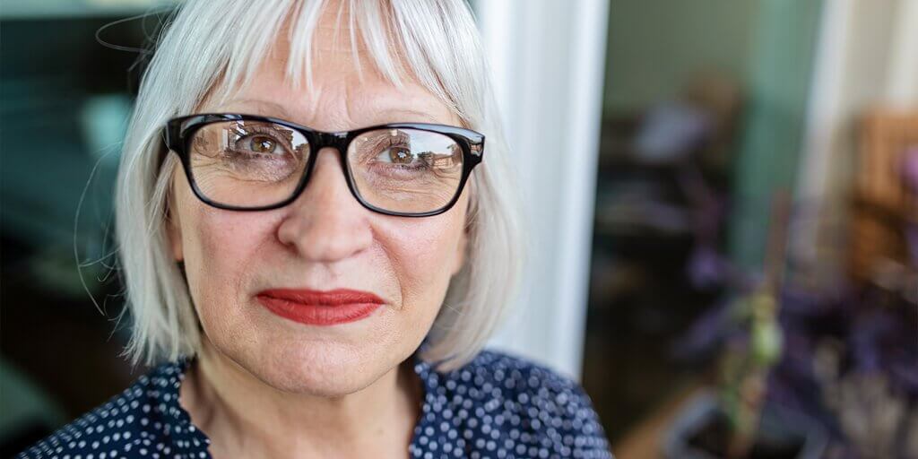 A senior woman wearing eyeglasses and smiling at the camera.